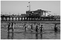 People bathing in ocean and Santa Monica Pier, late afternoon. Santa Monica, Los Angeles, California, USA ( black and white)