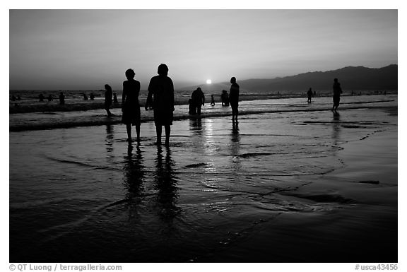 People and reflections on beach at sunset, Santa Monica Beach. Santa Monica, Los Angeles, California, USA (black and white)