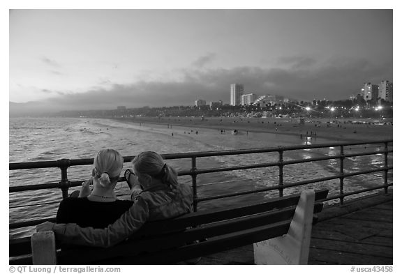 Two women sitting on bench at sunset , Santa Monica Pier. Santa Monica, Los Angeles, California, USA