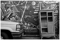 Car, mural, and discarded furniture, Mission District. San Francisco, California, USA (black and white)