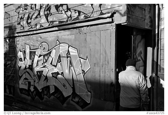 Man opening door of painted garage, Mission District. San Francisco, California, USA