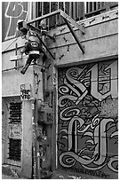 Painted garage door and suspended pinata figures, Mission District. San Francisco, California, USA (black and white)