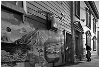 Mural and man entering house with grocery bags, Mission District. San Francisco, California, USA (black and white)