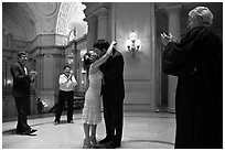 Just married couple kissing, witness and officiant applauding, City Hall. San Francisco, California, USA (black and white)