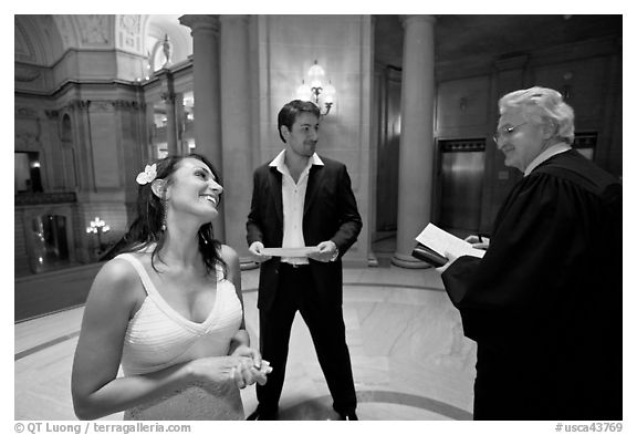 Bride and groom exchange smile with wedding official, City Hall. San Francisco, California, USA