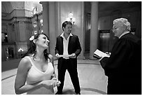 Bride and groom exchange smile with wedding official, City Hall. San Francisco, California, USA ( black and white)