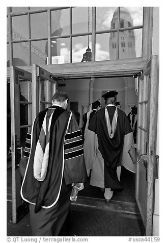Professors in academic regalia walk into door with Hoover tower reflected. Stanford University, California, USA (black and white)