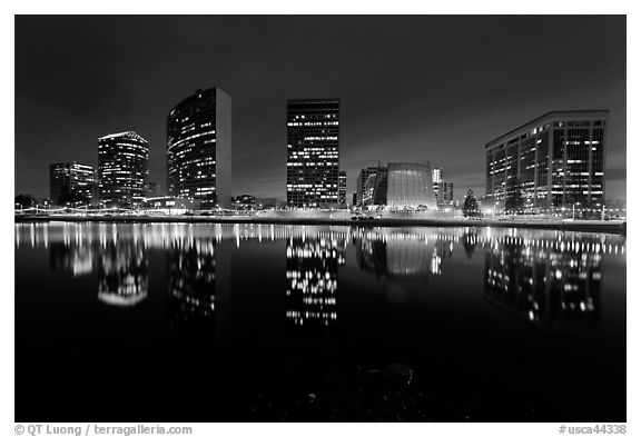 High-rise buildings and Oakland Cathedral reflected in Lake Meritt at night. Oakland, California, USA