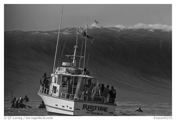 Judging boat with huge wave and surfer at crest. Half Moon Bay, California, USA (black and white)