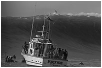 Judging boat with huge wave and surfer at crest. Half Moon Bay, California, USA (black and white)