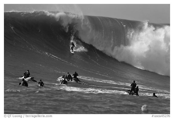 Surfer down huge wall of water observed from jet skis. Half Moon Bay, California, USA