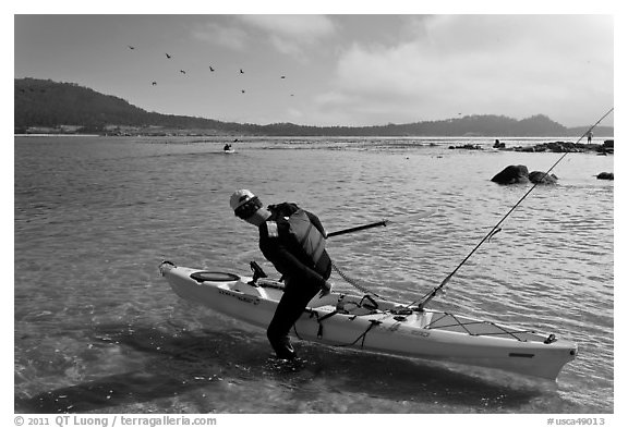 Man boards sea kayak, Carmel Bay. Carmel-by-the-Sea, California, USA