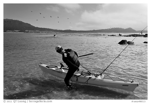 Man boards sea kayak, Carmel Bay. Carmel-by-the-Sea, California, USA (black and white)