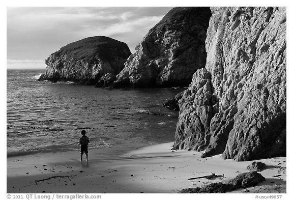 Boy standing at the base of bluff, China Cove. Point Lobos State Preserve, California, USA (black and white)