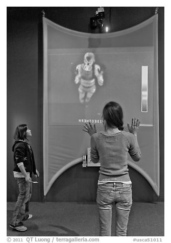 Girls play with thermal imaging camera, Tech Museum. San Jose, California, USA (black and white)