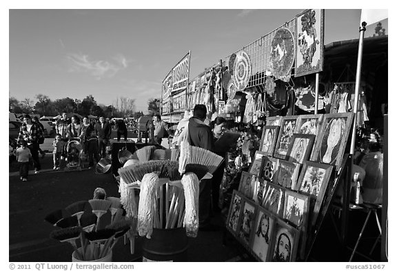 Brooms and religious pictures for sale, San Jose Flee Market. San Jose, California, USA (black and white)