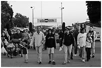 Families walking with entrance sign behind, San Jose Flee Market. San Jose, California, USA (black and white)