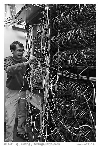Man with tangle of wires in server room. Menlo Park,  California, USA (black and white)