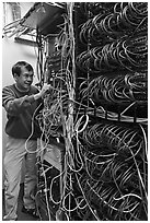 Man with tangle of wires in server room. Menlo Park,  California, USA (black and white)