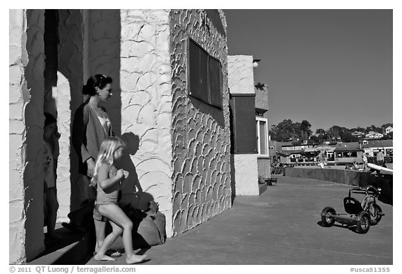Family steps out of colorful cottage. Capitola, California, USA (black and white)