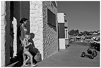 Family steps out of colorful cottage. Capitola, California, USA (black and white)