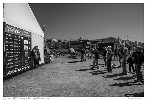 Spectators posing next to scoreboard with final standings. San Francisco, California, USA (black and white)