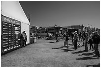 Spectators posing next to scoreboard with final standings. San Francisco, California, USA (black and white)