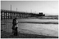 Couple embracing in front of Newport Pier. Newport Beach, Orange County, California, USA ( black and white)