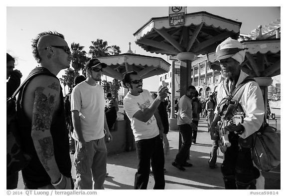 Tourists photograph Ocean Front Walk entertainer. Venice, Los Angeles, California, USA (black and white)