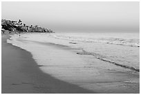 Beach at sunset with colors of sky reflected in wet sand. Laguna Beach, Orange County, California, USA ( black and white)
