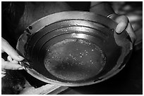 Hands holding pan with bits of gold, El Dorado County. California, USA ( black and white)