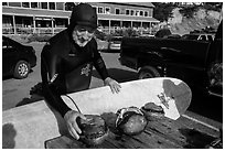 Man with surfboard examining abalone. California, USA ( black and white)