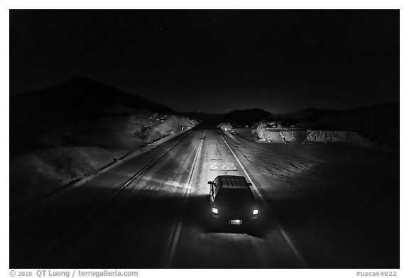 Aerial view of car shining headlights on highway 66 maker at night. Mojave Trails National Monument, California, USA (black and white)