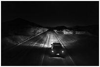 Aerial view of car shining headlights on highway 66 maker at night. Mojave Trails National Monument, California, USA ( black and white)