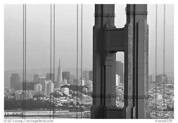 The city seen through the cables and pilars of the Golden Gate bridge, dusk. San Francisco, California, USA