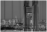 The city seen through the cables and pilars of the Golden Gate bridge, night. San Francisco, California, USA (black and white)
