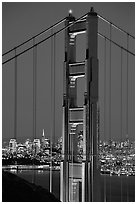 The city seen through the cables and pilars of the Golden Gate bridge, night. San Francisco, California, USA (black and white)