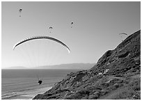 Paragliders soaring above cliffs, the Dumps, Pacifica. San Mateo County, California, USA (black and white)