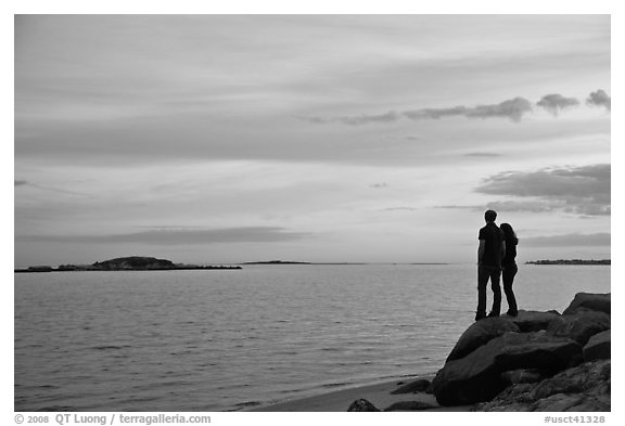 Couple standing on rock and Atlantic Ocean at sunset, Westbrook. Connecticut, USA (black and white)