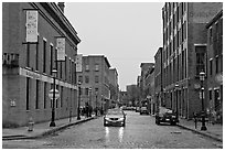 Downtown street lined with brick buildings in the rain, Lowell. Massachussets, USA ( black and white)