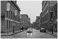 Downtown street lined with brick buildings in the rain, Lowell. Massachussets, USA (black and white)