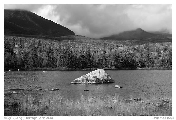 Boulder, pond, forest in autumn and mountains with clouds. Baxter State Park, Maine, USA