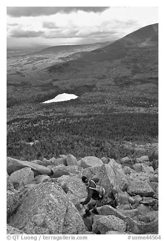 Hiker descends from summit amongst boulders above treeline. Baxter State Park, Maine, USA (black and white)