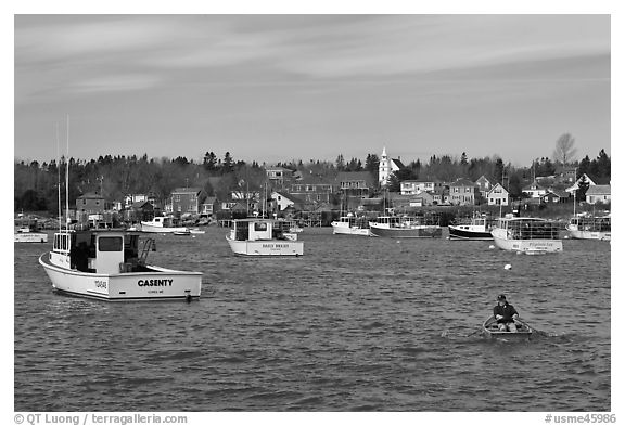 Man paddling to board lobster boat. Corea, Maine, USA (black and white)