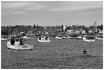 Man paddling to board lobster boat. Corea, Maine, USA (black and white)