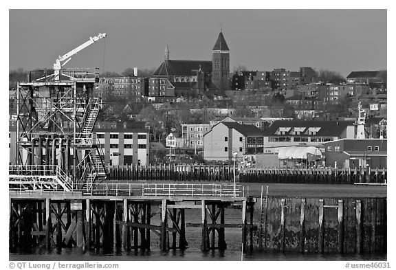 Pier and hillside buildings across harbor. Portland, Maine, USA (black and white)