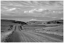 Gravel road, rolling hills and badlands. North Dakota, USA (black and white)