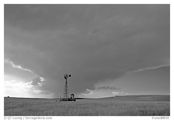 Windmill and tractor under a threatening stormy sky. North Dakota, USA (black and white)