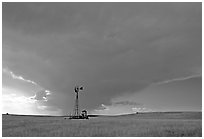 Windmill and tractor under a threatening stormy sky. North Dakota, USA (black and white)