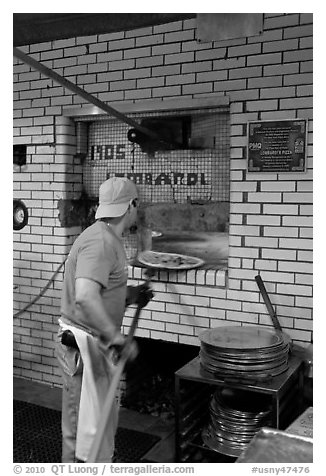 Man loading pizza into oven, Lombardi pizzeria. NYC, New York, USA (black and white)